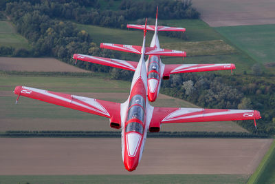 Red airplane flying over field