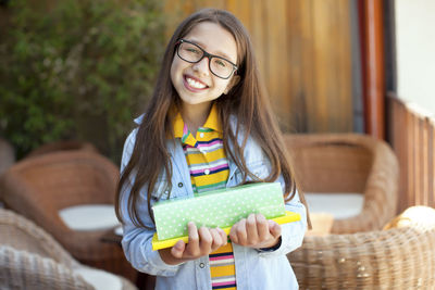 Smiling young woman using mobile phone while standing on camera