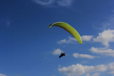 Low angle view of person paragliding against sky