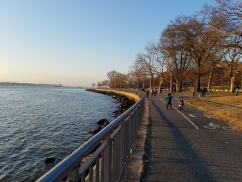 Scenic view of sea by road against clear sky during sunset