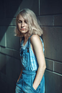 Beautiful young woman standing against wall