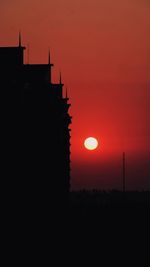 Low angle view of silhouette building against orange sky