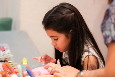 Side view of girl making craft doll