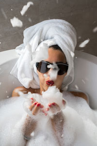 Woman blowing foam in the bathtub