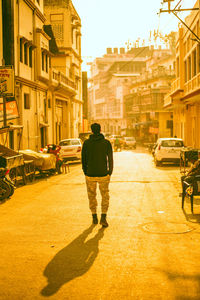 Rear view of man walking on street in city