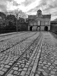 Cobblestone street by building against sky