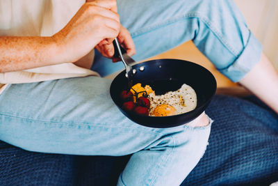 Midsection of person holding food in cooking pan