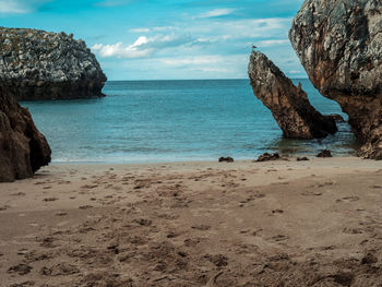 Rock formation on beach against sky