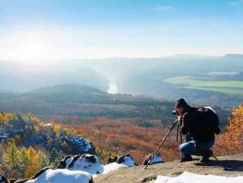 Professional photographer takes photos with mirror camera and tripod on snowy peak. dreamy fog