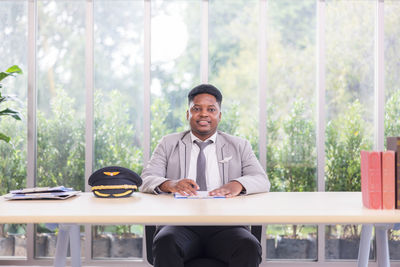 Portrait of young man sitting on table at home