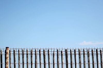 Wooden posts in sea against clear blue sky