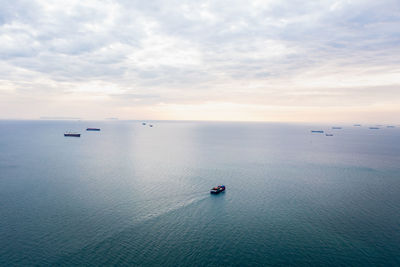 Aerial seascape view and small container ship floating in sea horizon and cloud sky background 