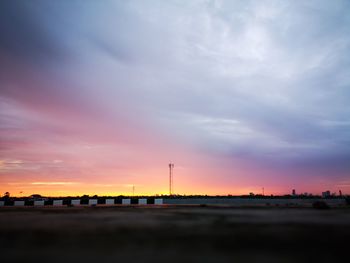 Silhouette factory against sky during sunset