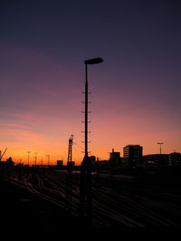 Silhouette of railroad tracks against sky during sunset