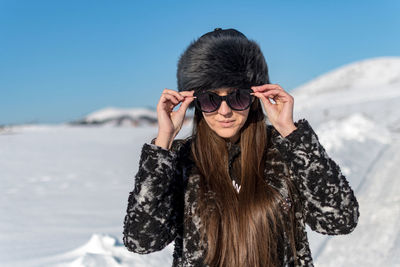 Young woman wearing sunglasses against mountain during winter