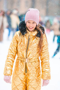 Portrait of smiling young woman standing against snow