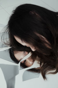 Woman by broken mirror with reflection on floor