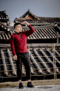 Full length of man shielding eyes while standing on land against buildings