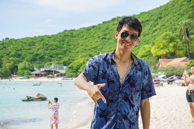 Portrait of young man wearing sunglasses while standing at beach