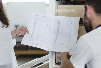 Interior designer showing design of drawer to carpenter while standing at workshop