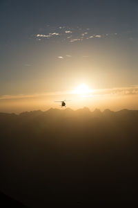 Silhouette helicopter against sky during sunset