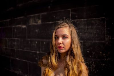 Portrait of young woman standing against wall