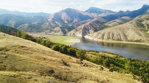 Scenic view of lake by mountains against sky