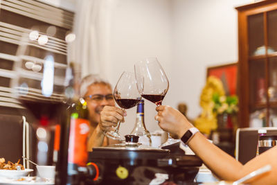 Couple making toast with glasses of red at dinner.