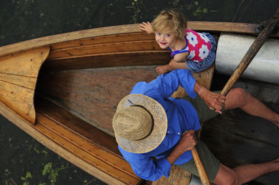 Happy little girl with her grandfather in rowing boat, top view