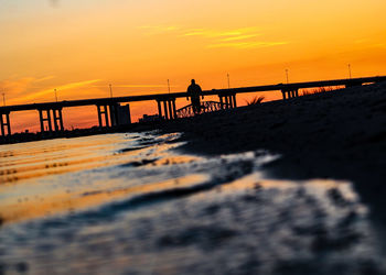 Silhouette man on beach against sky during sunset