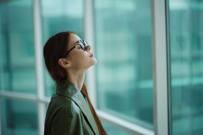 Young woman looking through window