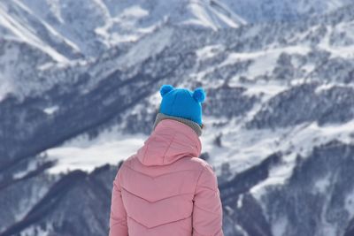 Rear view of woman standing against snowcapped mountain