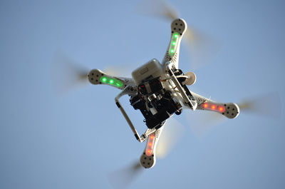 Low angle view of flying drone against clear sky