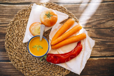 Top view of vegan pumpkin cream in an enameled mug with vegetables, peppers leek and tomatoes