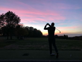 Rear view of silhouette man standing by tree against sky during sunset