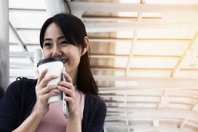 Close-up of woman holding coffee against ceiling