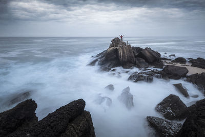 Scenic view of rocks in sea against sky