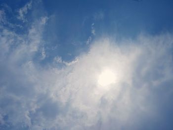 Low angle view of sunlight streaming through clouds