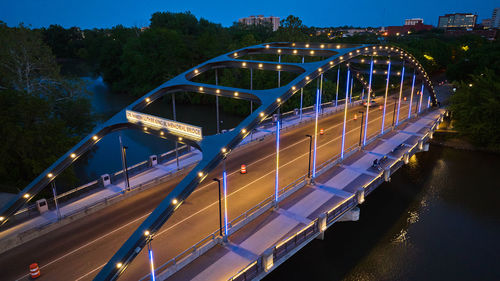 Illuminated bridge over river against sky at night