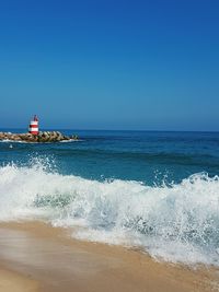 Waves rushing towards shore against clear sky