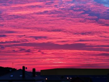 Silhouette city against dramatic sky during sunset