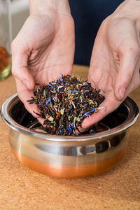 Midsection of woman filling petals in bowl at home