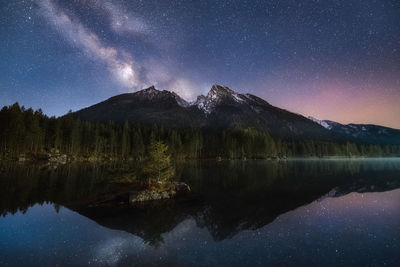 Scenic view of lake by mountains against sky at night