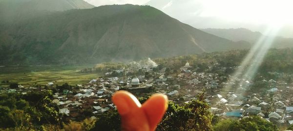Low section of person hand on water against mountain