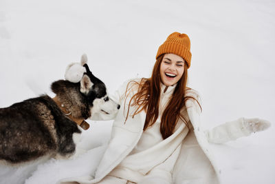 Portrait of young woman with dog on snow