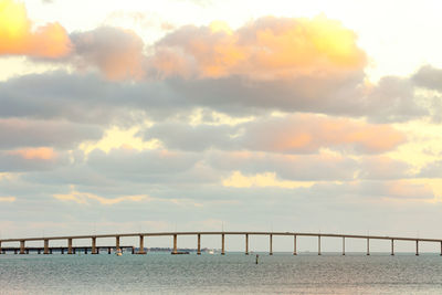 Bridge over sea against sky during sunset