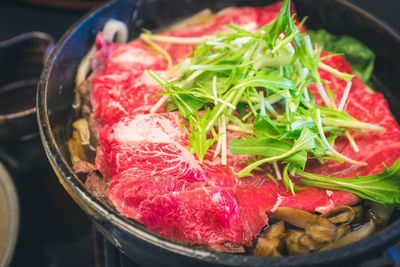 Close-up of raw meat and vegetable in utensil on table