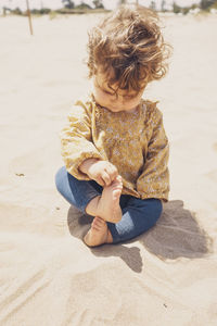 Girl sitting on sand at beach