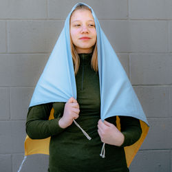 Caucasian blond teenager wrapped in an ukrainian flag over a neutral background