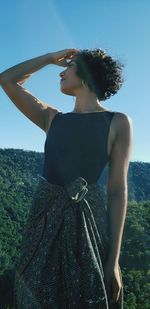 Rear view of woman standing by tree against sky